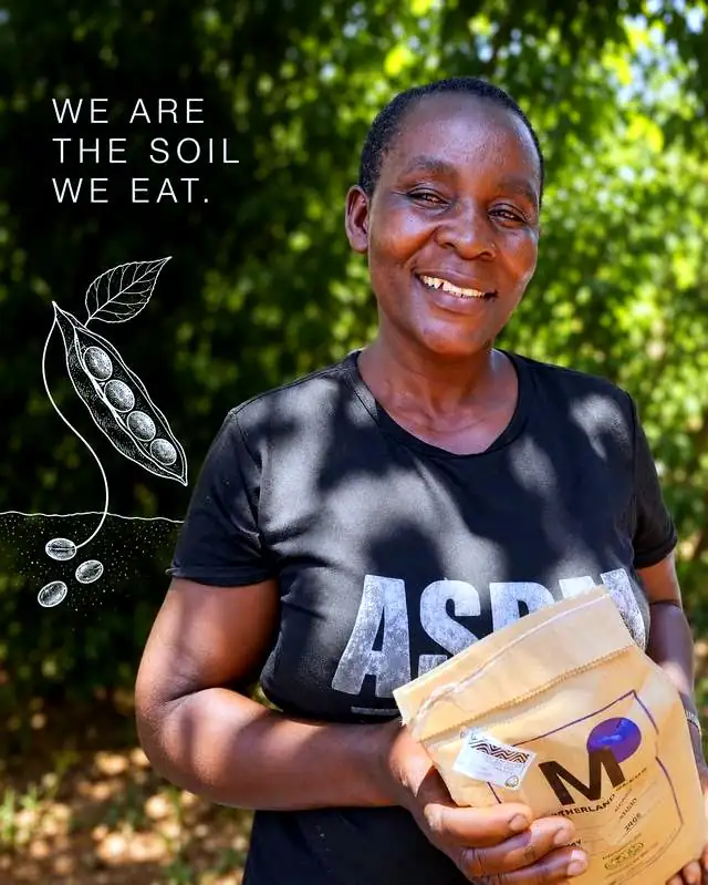 Eine MOTHERLAND-Bäuerin aus Siaya County hält Saatgutpackungen von MOTHERLAND. We are the soil we eat.