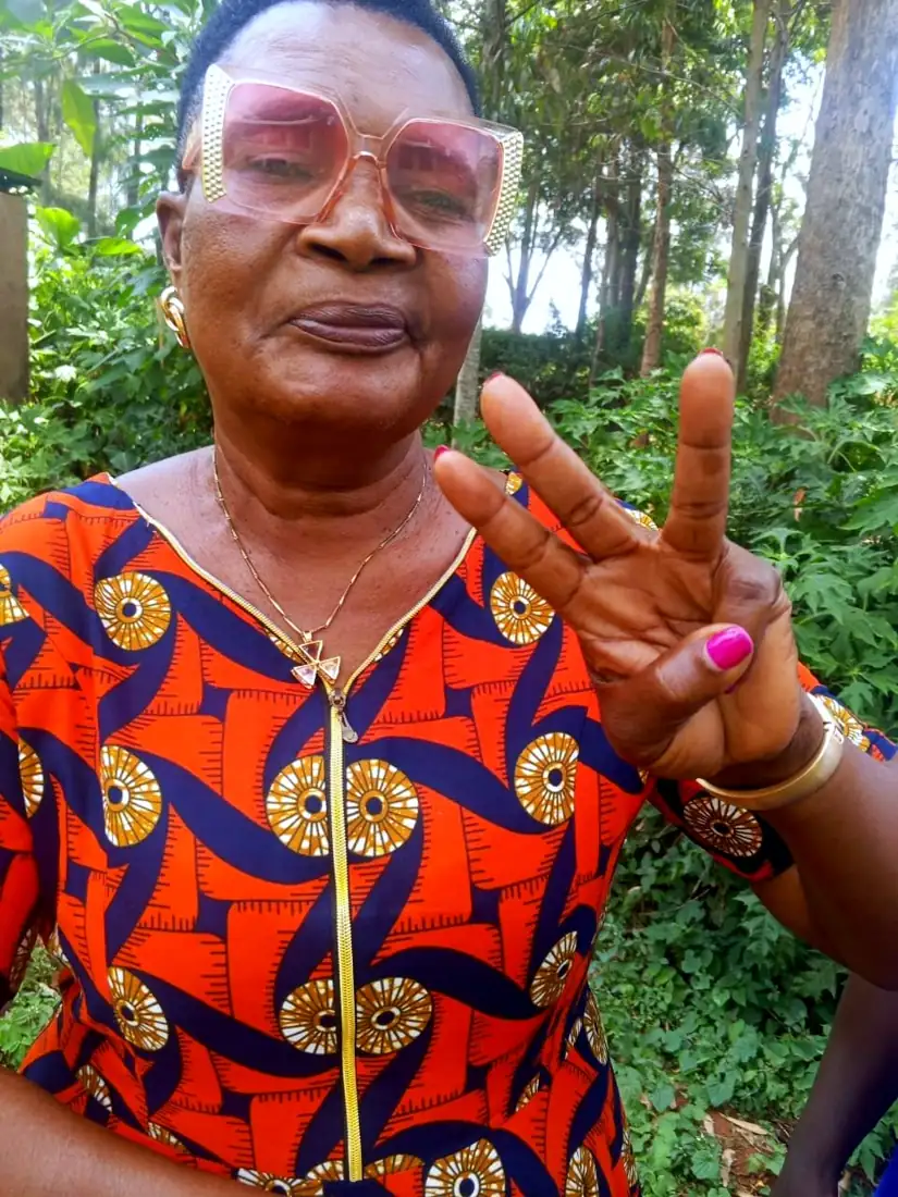 Eine Bäuerin aus Siaya County mit Sonnenbrille zeigt das Peace-Zeichen