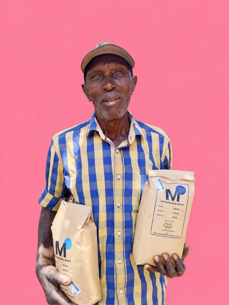 Bauer mit Kappe und zwei Tüten MOTHERLAND SEEDS vor pinkem Hintergrund, Siaya, Kenia